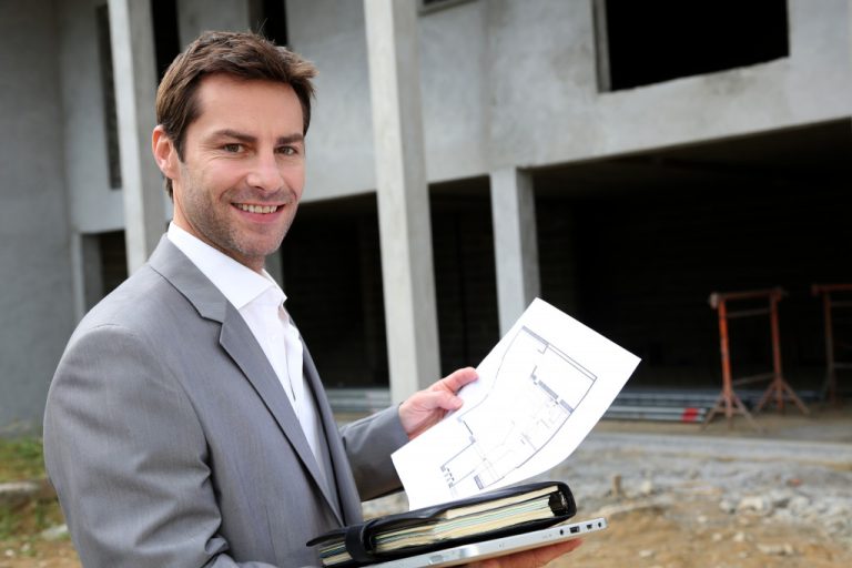 a young real estate agent in front of a building under construction