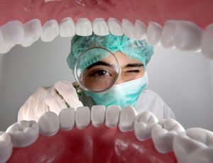 dentist holding a magnifying glass examining teeth